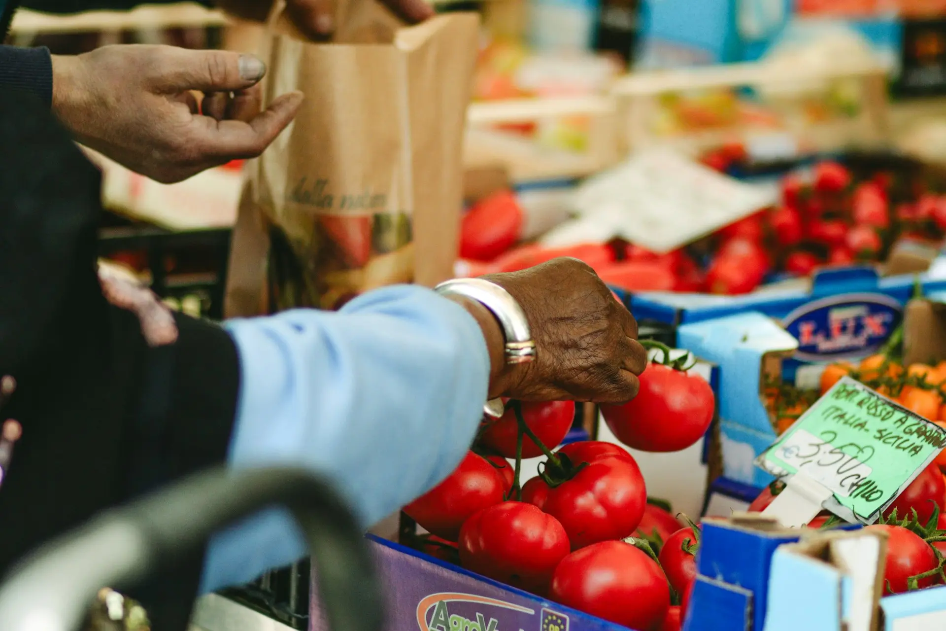 a person handing a bag of tomatoes to another person